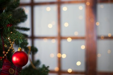 Şenlikli arka planda çam dallarında asılı parlak Noel kırmızı topu.