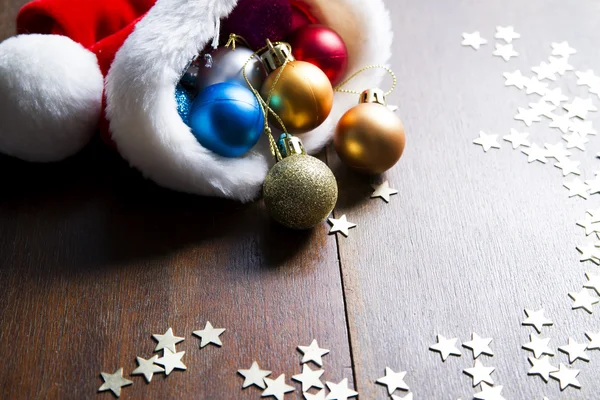 Christmas balls and Santa hat on wood background — Stock Photo, Image