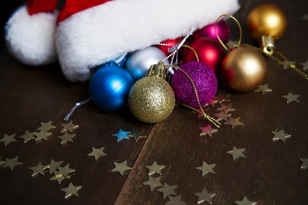 Noel topları ve ahşap arka plan üzerinde Santa şapka — Stok fotoğraf