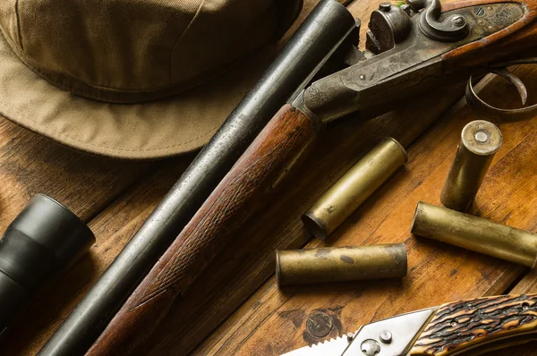 Puška lovecká, munice, nůž a čepici na stůl — Stock fotografie