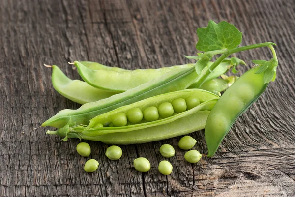 Pods of green peas on a wooden surface — Stock Photo, Image