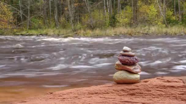 Tempo Cairn Lapso Pedras Uma Rocha Vermelha Pelo Rio — Vídeo de Stock