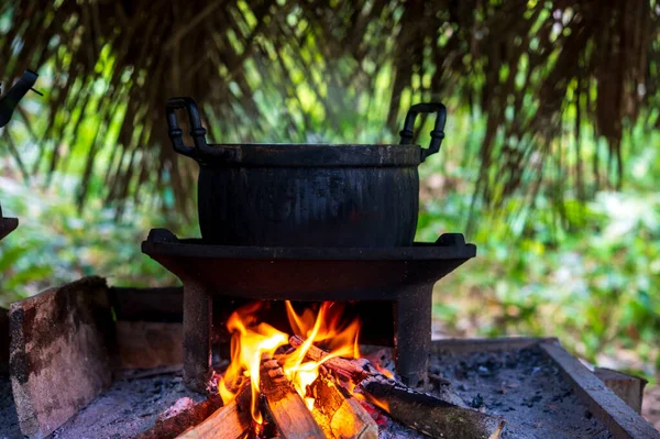 Old pot on firewood stove with wood burning, cooking food in rural kitchen at Thailand