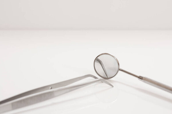 Metal mirror and tweezers. Dental instruments for dental treatment on the black background. Medical tools. Close-up view. Shallow depth of field. Focus on a metal mirror.