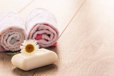 Banyo prosedürleri için beyaz havlu ve sabun ve tahta tahtalarda papatya çiçeği. Spa ürünleri ve aksesuarları