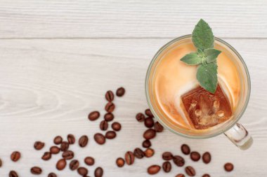 Bir bardak lezzetli milkshake ya da çikolatalı buzlu smoothie ve beyaz arka planda kahve çekirdekli nane yaprakları. Üst görünüm.