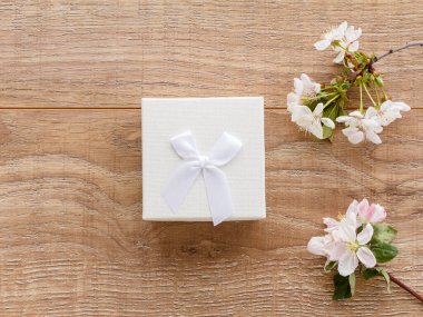 Ağaç zemin üzerinde çiçek açan kiraz dalları ve elma ağaçları olan hediye kutusu. Üst Manzara. Tatillerde hediye verme kavramı.