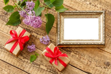 Fotokopi alanı, leylak çiçekleri ve eski ahşap tahtalarda hediye kutuları olan eski bir fotoğraf çerçevesi. Üst görünüm.