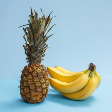 Tropikal meyveli doğal bileşim. Mavi arka planda taze ananas ve muzlar..