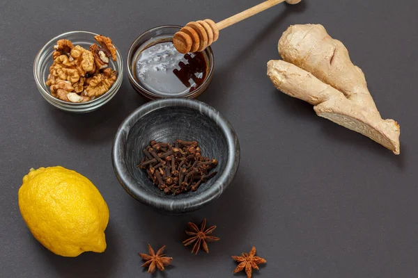 Health remedy foods for cold and flu relief with lemon, ginger, honey, almond and walnuts on the black background. Top view. Foods That Boost the Immune System.