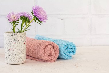 Beyaz arka planda çiçek ve havlu konservesi. Kadın kozmetik ürünleri ve aksesuarları.