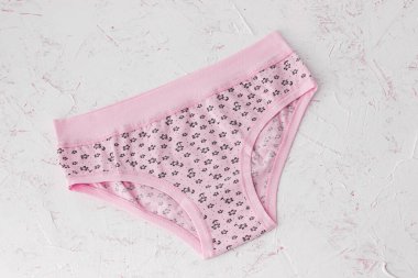 Beyaz yapılı arka planda pembe pamuklu külotlar. Kadın iç çamaşırı seti. Üst görünüm.