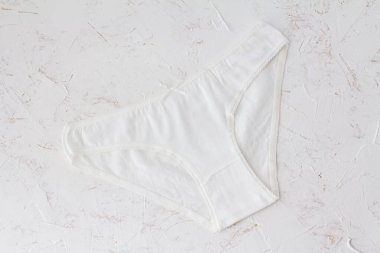 Beyaz yapılı arka planda beyaz pamuklu külotlar. Kadın iç çamaşırı seti. Üst görünüm.