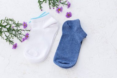 Beyaz yapılı arka planda iki çift kadın çorabı ve çiçek..