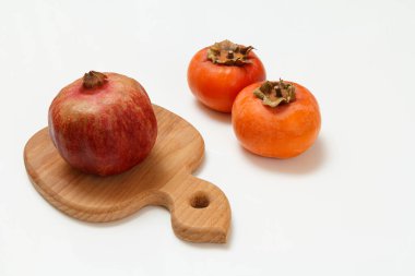 Tahta kesme tahtası, olgun nar ve beyaz arka planda hurma meyveleri. Organik meyveler.