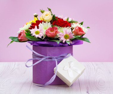 Bir buket kır çiçeği ve tahtanın üzerinde bir hediye kutusu..