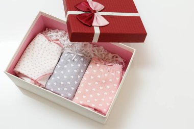 Beyaz arka plandaki bir kutuda farklı renklerde katlanmış pamuk külotlar. Kadın iç çamaşırı seti. Üst görünüm.