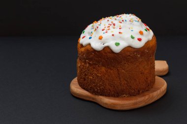 Ahşap kesim tahtasının üzerinde siyah arka planlı tatlı Paskalya pastası.