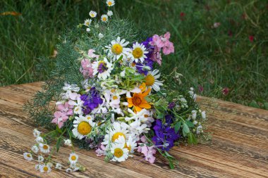 Yeşil doğal arka planı olan eski ahşap tahtalarda bir buket kır çiçeği..