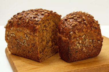 Beyaz arka planı olan tahta kesme tahtasının üzerinde çavdar ekmeği kes..