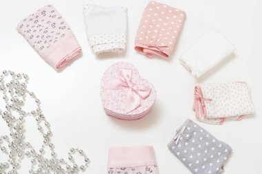 Farklı renklerde katlanmış pamuk külotlar, bir hediye kutusu ve beyaz arka planda boncuklar. Kadın iç çamaşırı seti. Üst görünüm.