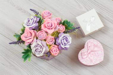 El yapımı çiçekler ve gri ahşap arka planda hediye kutuları. Tatillerde hediye verme kavramı. Üst görünüm.