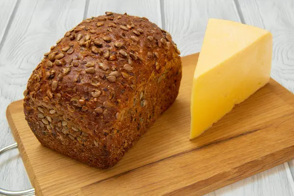 Loaf of bread on wooden cutting board on white background — Stock Photo, Image