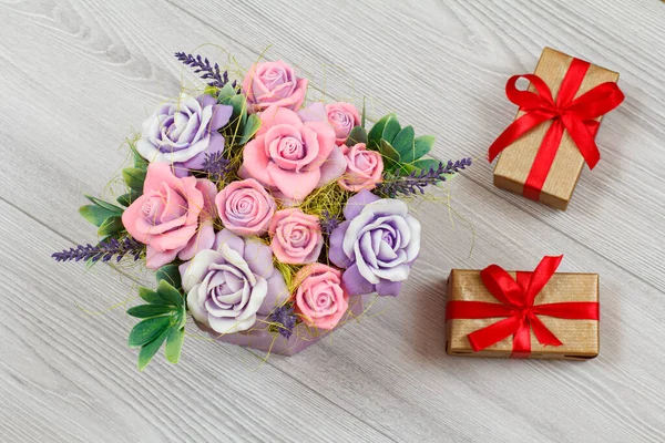 Handmade flowers and gift boxes on the gray wooden background. Concept of giving a gift on holidays. Top view.