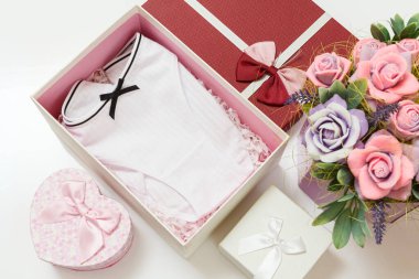 Beyaz arka planda suni çiçekler olan bir kutuda katlanmış pamuk külotlar. Kadın iç çamaşırı seti. Üst görünüm.