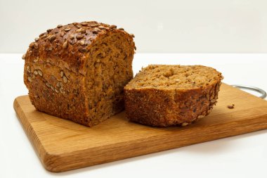 Beyaz arka planı olan tahta kesme tahtasının üzerinde çavdar ekmeği kes..