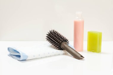 Bir şişe şampuan, sabun, havlu ve beyaz arka planda bir tarak. Kadın kozmetik ve aksesuarları.