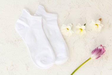 Bir çift beyaz çorap, bir lale ve beyaz yapılı arka planda nergis çiçeği tomurcukları, Üst Manzara.