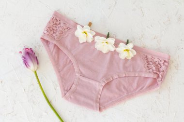 Üzerinde nergis çiçeği tomurcukları olan pembe pamuklu külotlar ve beyaz yapılı bir lale. Kadın iç çamaşırı seti. Üst görünüm.