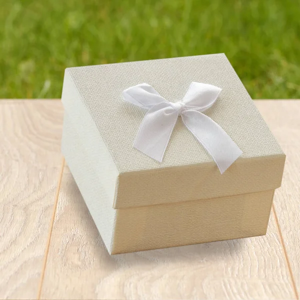 Gift box on wooden boards with green natural background. — Stock Photo, Image