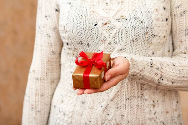 Mujer sosteniendo una caja de regalo atada con cinta roja en la mano. — Foto de Stock