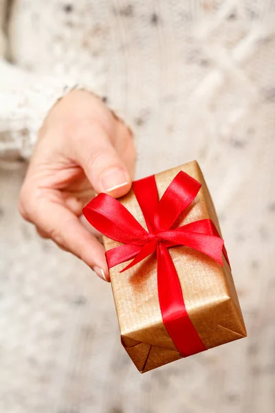 Mujer sosteniendo una caja de regalo atada con cinta roja en la mano. — Foto de Stock