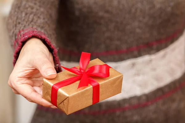 Mujer sosteniendo una caja de regalo atada con cinta roja en la mano — Foto de Stock