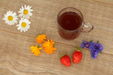Çilekli ve çiçekli bir bardak çay.