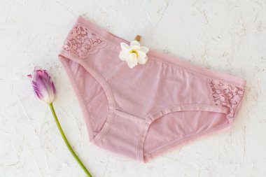 Üzerinde nergis çiçeği tomurcuğu olan pamuk külotlar ve arka planda beyaz bir lale. Kadın iç çamaşırı seti. Üst görünüm.