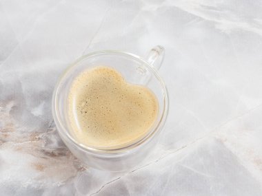 Mutfak masasının üzerinde kalp şeklinde bir bardak kahve. Üst görünüm.