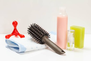 Bir şişe şampuan, aroma yağı, sabun, havlu ve beyaz arka planda bir tarak. Kadın kozmetik ve aksesuarları.