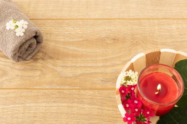 Vücut bakımı ürünleri. Yumuşak havlu ve ahşap arka planda bir mum. Spa ve vücut bakımı seti. Üst görünüm.