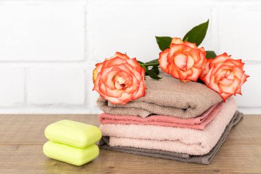Yumuşak havlular, kırmızı gül çiçekleri ve ahşap zeminde sabun olan spa kompozisyonu.