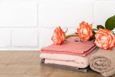 Ahşap zeminde kırmızı gül çiçekleri olan yumuşak havlu yığını..