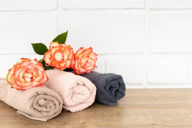 Ahşap zeminde kırmızı gül çiçekleri olan yumuşak havlu yığını..