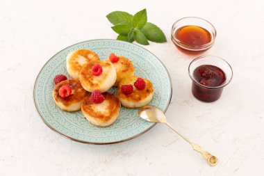 Ahududu ve nane yapraklı ev yapımı kremalı börek. Çilek reçelli cam kaseler ve beyaz arka planda bal. Üst görünüm.