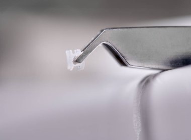 Ortodontik parantez içinde makro atışı. Diş kıvrımlarını tedavi etmek ve dişçiye güzel bir gülümseme yaratmak için yardımcı detaylar. Gri arkaplanda seramik desteğe sahip çelik forseps.