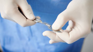 Plastik cerrahi için neşter hazırlayan doktor ellerine yakın durun. Kollarında paslanmaz çelik tıbbi aletlerle beyaz steril eldiven takan bir cerrah. Cerrahi ve tıp kavramı.