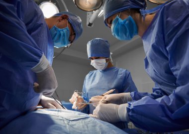Tıbbi aletler kullanan ve modern klinikte estetik ameliyat yapan mavi takım. Tıp, abdominoplasti ve estetik cerrahi kavramı.