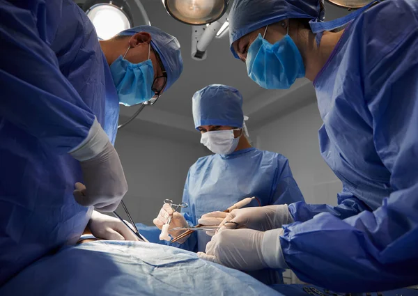 青い医療スーツの外科チームは 医療機器を使用し 現代のクリニックで審美的な手術を実行します 整形外科 整形外科の概念 — ストック写真